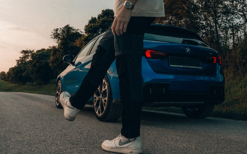 Person behind a parked blue BMW